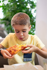 Caucasian boy eating a slice of pizza in a pizzeria