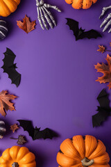 Pumpkins, bats, and skeleton hands on a purple background, perfect for Halloween decorations. Copy space. Flat lay. Top view