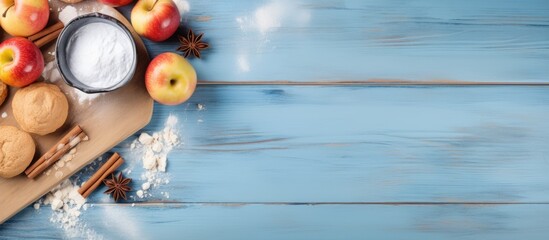 The bakery background showcases homemade apple pie or cake concept It includes apples wheat flour eggs a cinnamon spoon and an egg whisk arranged on a blue wood table The top view flat lay provides a