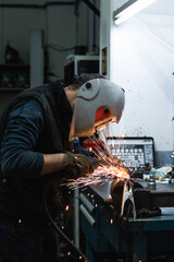 Man welding a metal piece in the garage