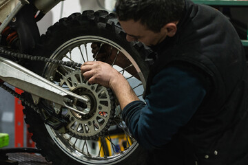 mechanic worker checking motorbike replacing bike wheel and tyre in auto repair shop store service. worker maintenance examining and installing wheel tire at garage.