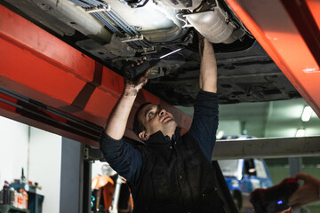 Mechanic examining under the car at the repair garage.