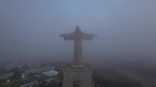 Sanctuary of Christ the King-Portugal statue in the fog and the city behind it in Lisbon, Portugal