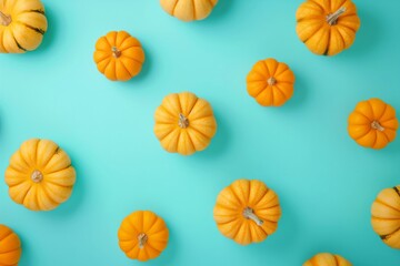 A pattern of small orange pumpkins arranged on a turquoise background, ideal for autumn or Halloween-themed designs.