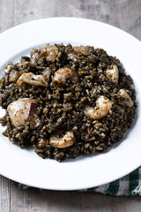 Black rice with seafood in plate on wooden table