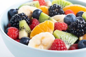 Fruit salad in a blue bowl isolated on white background. Close up