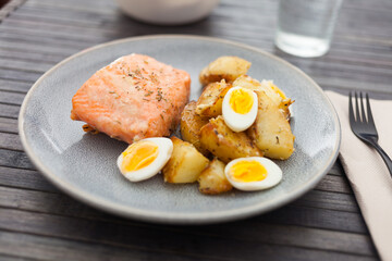 Baked salmon fillet with fried potato wedges and quail eggs halves
