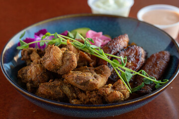 Fresh Chicharron de pollo vegetables and meat in a bowl with sauce on a table