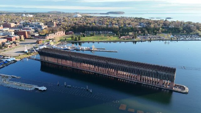 A drone view of a large dock with cityscape and other water structures in the background