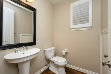 Bathroom featuring a toilet, sink, and adjacent mirror