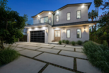 House with a tiled driveway and lush greenery in the garden. California, USA