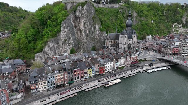 Ascending drone shot of the riverfront buildings and Notre Dame de Dinant Church in Dinant, Belgium