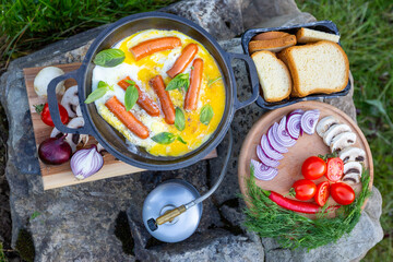 Cooking food in a frying pan, near a fire in the open air.