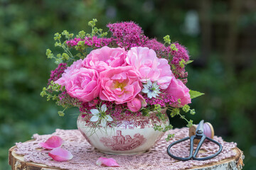 romantisches Blumengesteck mit pink Rosen, Jungfer im Grünen, Frauenmantel und Sommerspiere-Blüten in vintage Zuckerdose