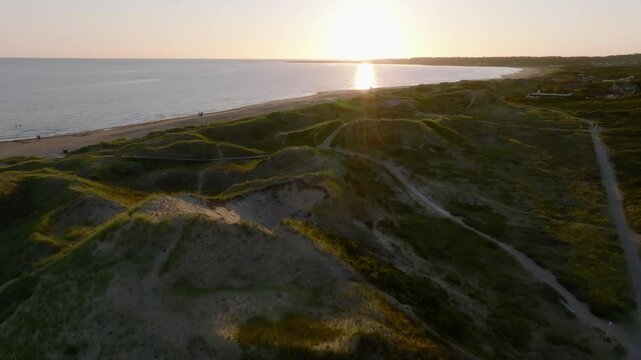 Sand hills and beach with green grass in sunset