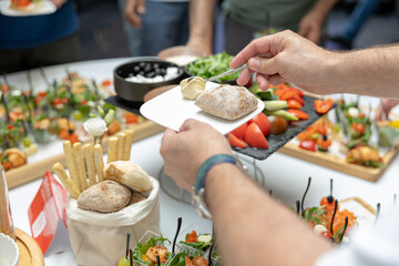 Buffet. Hands laying food on a plate. Hands place bun and pate on plate. Catering