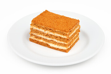Piece of honey cake in a plate on a white background