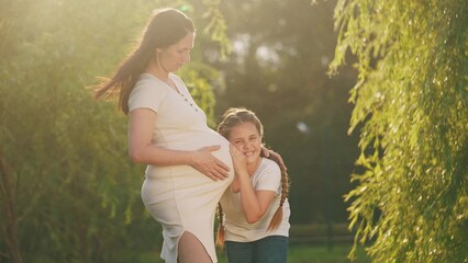 girl pregnant woman. daughter hugging her pregnant mother's belly. girl pregnant woman happy family kid dream concept. the girl loves her unborn brother, lifestyle mother equally loves two children