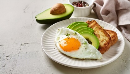 Keto breakfast fried egg, avocado and bread in a white plate. Keto diet concept.