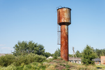 Old rusty water tower on blue sky background