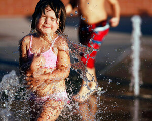 a young girl playing with water in front of a fountain