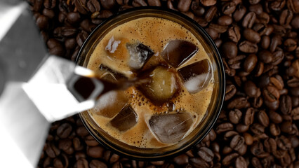 Make iced coffee. Pouring espresso in glass with ice cubes, top view