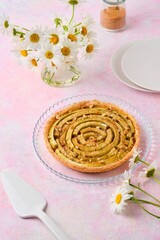 Tart on a sand dough with rhubarb and walnuts laid out in a circle in pink for baking on a pink concrete background. Recipes for rhubarb.