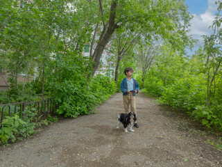 handsome boy with a dog on a leash. walking pets. Cavalier King Charles Spaniel, tricolor. Soft focus