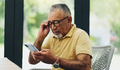 Glasses, phone and mature man reading news, email or crossword puzzle on internet in home....