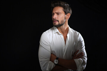 Handsome man in white shirt with crossed arms looking to the side