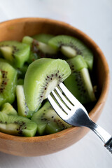 Kiwi and kiwi fruit salad in wooden bowl, selective focus