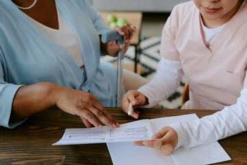 Nurse helping elderly African American woman with filling papers out