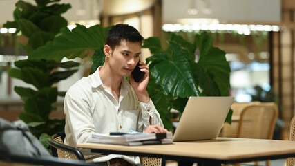 Businessman having phone conversation using laptop at modern coworking space