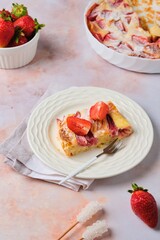 A piece of pies from the dough of the Filo with strawberries and cream on a white plate on a marble pink background. Strawberry recipes.