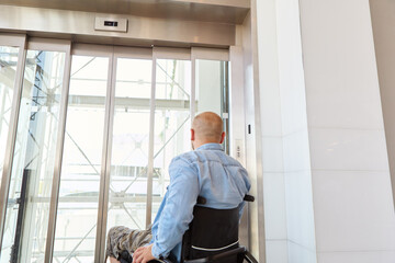 Man in wheelchair waiting by the elevator in a modern building © Robert Kneschke