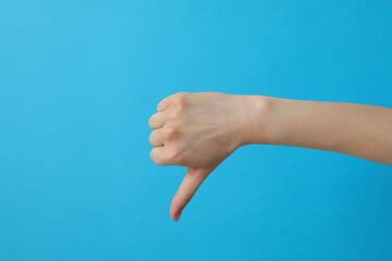 Female hand showing finger down on blue background