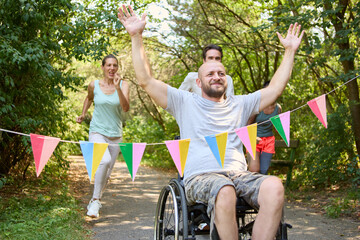 Cheerful person in a wheelchair finishing a race with high five and friends supporting