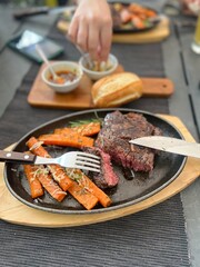 Grilled Steaks with spices rosemary and pepper on wooden board on black background.