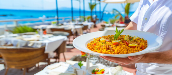 Waiter carrying a plate of paella in a beach bar