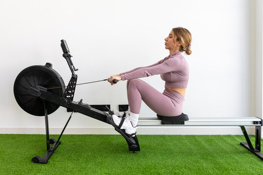 Woman in pink sportswear using a rowing machine at gym