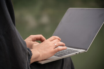 A woman is typing on a laptop with a ring on her finger. Concept of productivity and focus, as the...