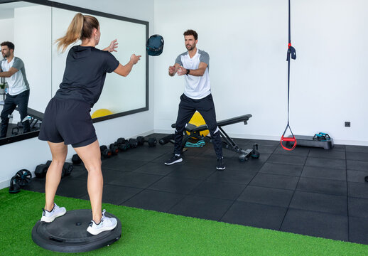 Trainer instructing a female athlete in a modern gym setting