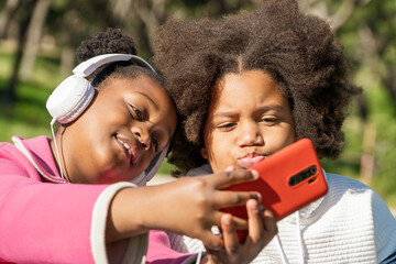 Two girls enjoying music and making selfies in the park