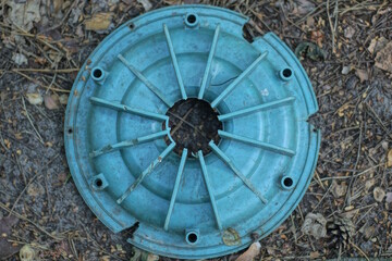 one big blue lid with a hole from a household appliance lies on the gray ground outside