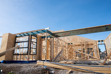 The wooden frame of a suburban house with timber trusses at a construction site. An unfinished home building project. Concept of property investment,  the real estate and housing market.
