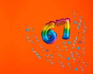 Multicolor balloon number 67 - Confetti explosion on orange background. Birthday card