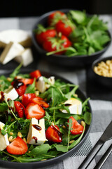 Summer salad with strawberries, arugula, Camembert cheese and pine nuts.