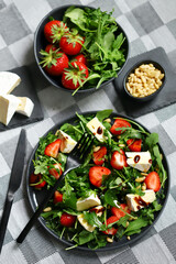 Summer salad with strawberries, arugula, Camembert cheese and pine nuts.