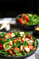 Summer salad with strawberries, arugula, Camembert cheese and pine nuts.