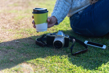 Fototapeta premium Woman drinking coffee in sun sitting outdoor in sunshine light enjoying her morning coffee